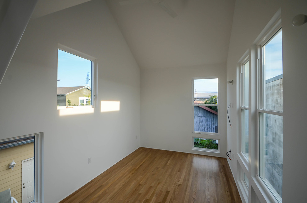 Kleines Modernes Hauptschlafzimmer mit weißer Wandfarbe und hellem Holzboden in New Orleans