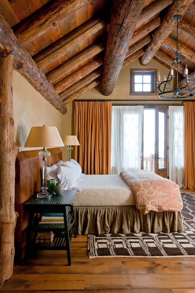 Immagine di una camera da letto rustica con pareti beige e pavimento in legno massello medio