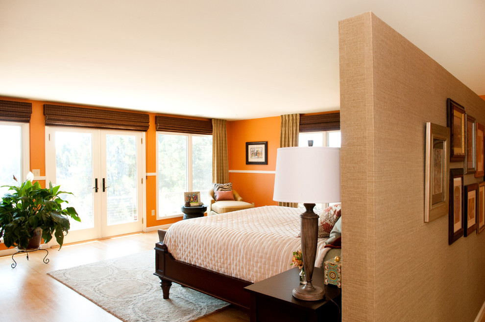 Esempio di una grande camera matrimoniale design con pareti arancioni, pavimento in legno massello medio e nessun camino