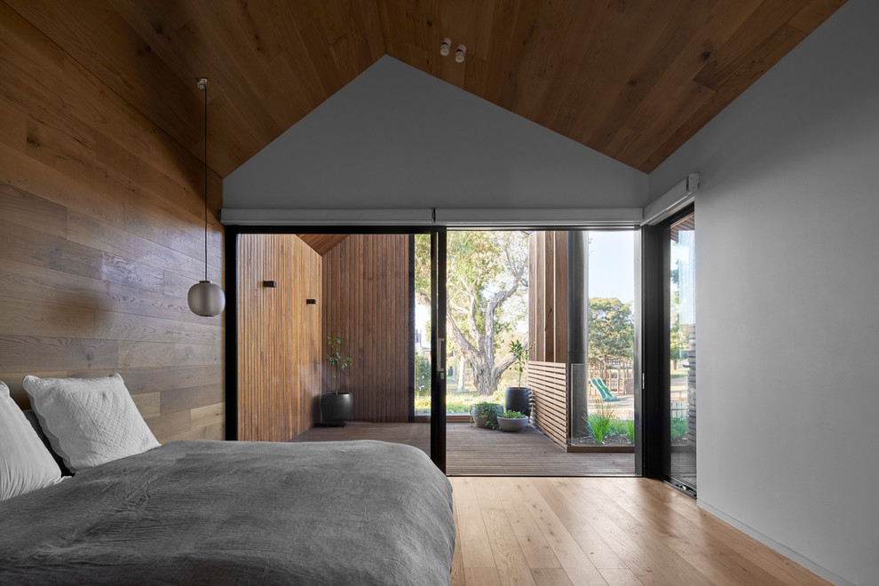Immagine di una camera matrimoniale minimal con pareti marroni e pavimento in legno massello medio