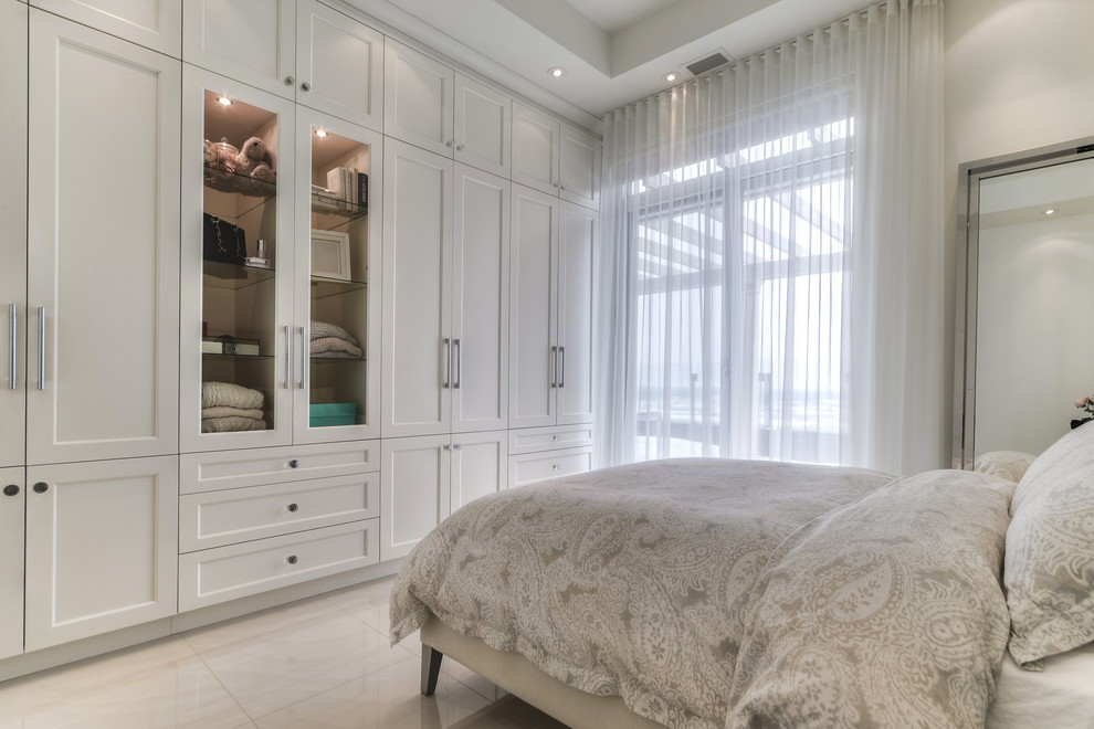 Immagine di una camera degli ospiti minimal di medie dimensioni con pareti bianche, pavimento in marmo, camino sospeso, cornice del camino in intonaco e pavimento bianco