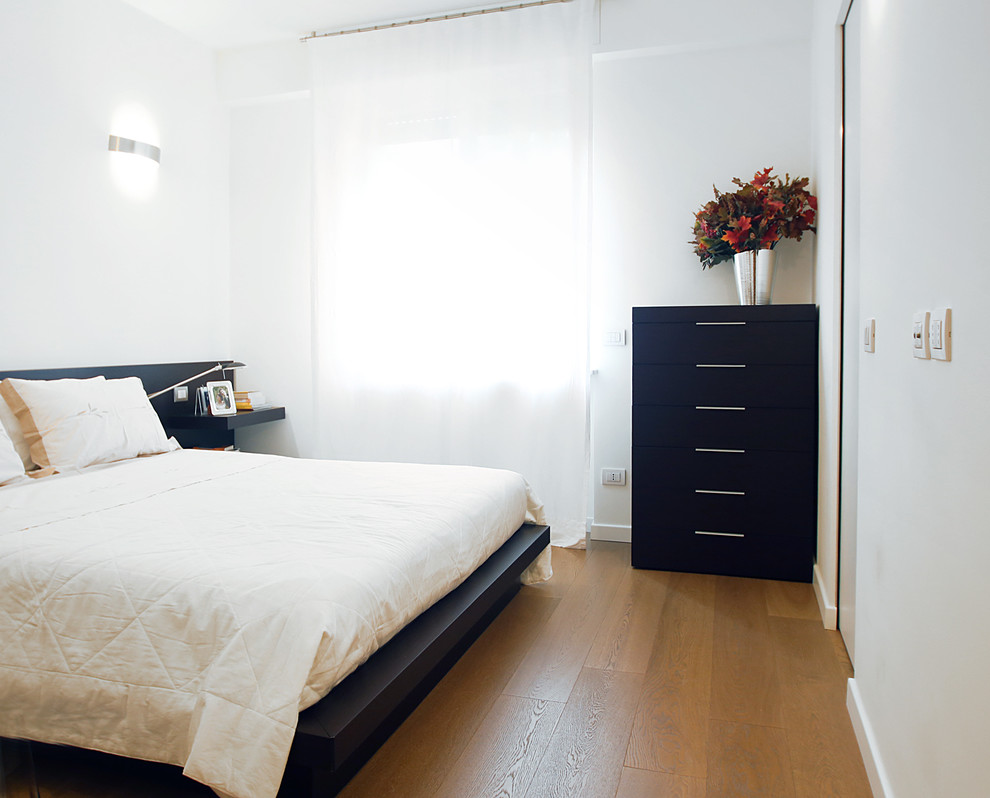 Foto di una piccola camera matrimoniale minimal con pareti bianche e pavimento in legno massello medio