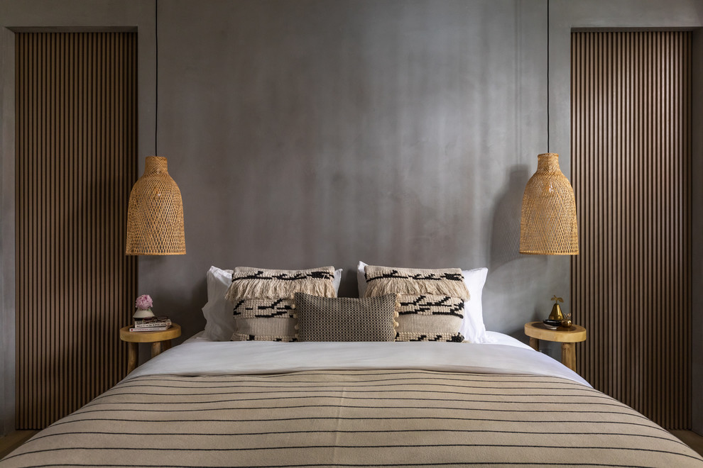Imagen de dormitorio principal minimalista de tamaño medio con paredes grises, suelo de madera clara y suelo marrón