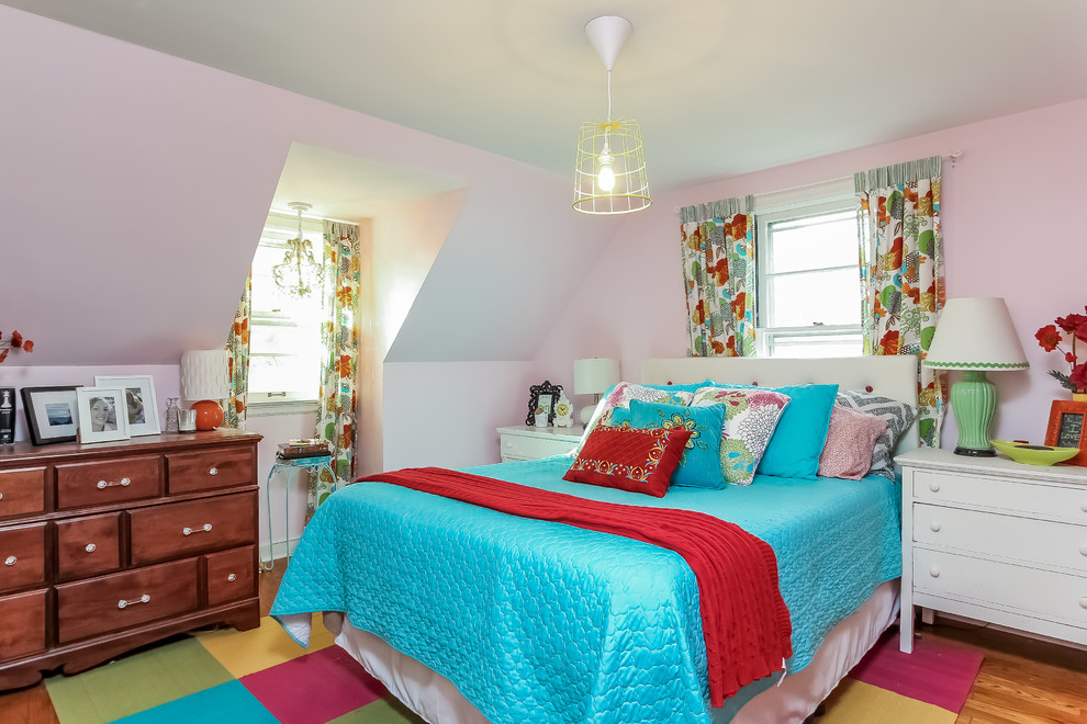 Cette image montre une petite chambre parentale bohème avec un mur rose et parquet foncé.