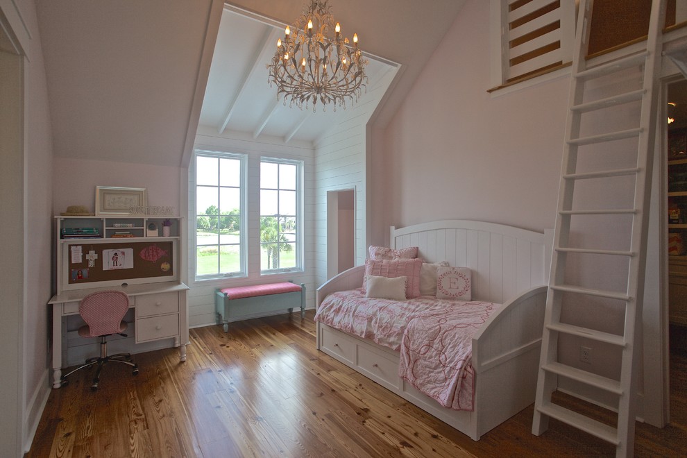 Modelo de dormitorio tipo loft costero sin chimenea con paredes rosas y suelo de madera en tonos medios