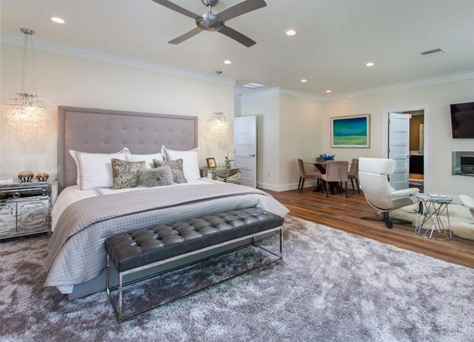 Expansive contemporary master bedroom in Tampa with white walls, medium hardwood flooring, a two-sided fireplace and brown floors.