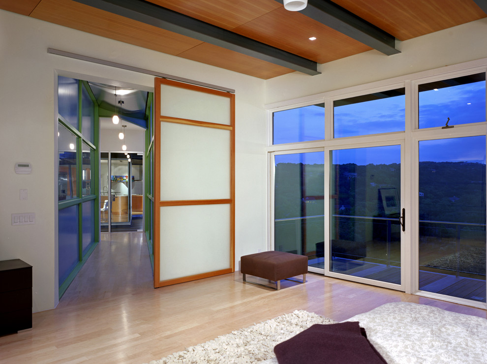 Mittelgroßes Modernes Hauptschlafzimmer ohne Kamin mit weißer Wandfarbe, braunem Holzboden und beigem Boden in Austin