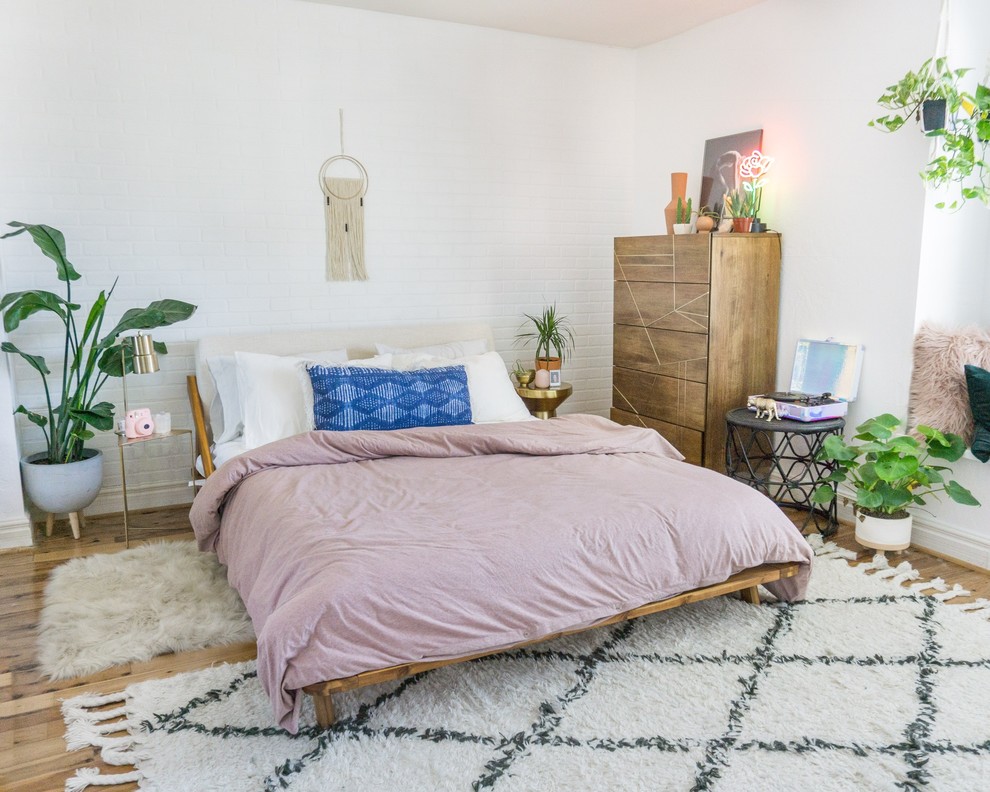 На фото: хозяйская спальня среднего размера в стиле фьюжн с белыми стенами, паркетным полом среднего тона, горизонтальным камином и коричневым полом с