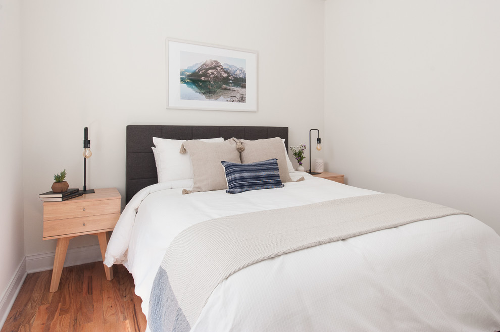 Modelo de habitación de invitados escandinava pequeña con paredes blancas y suelo de madera en tonos medios