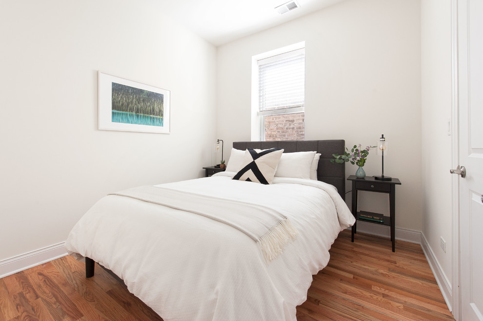 Réalisation d'une petite chambre d'amis design avec un mur blanc et un sol en bois brun.