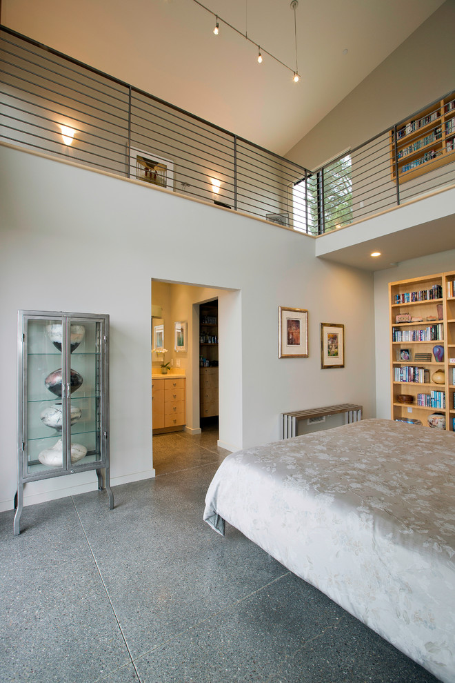 Foto di una camera da letto design con pavimento in cemento e pareti grigie