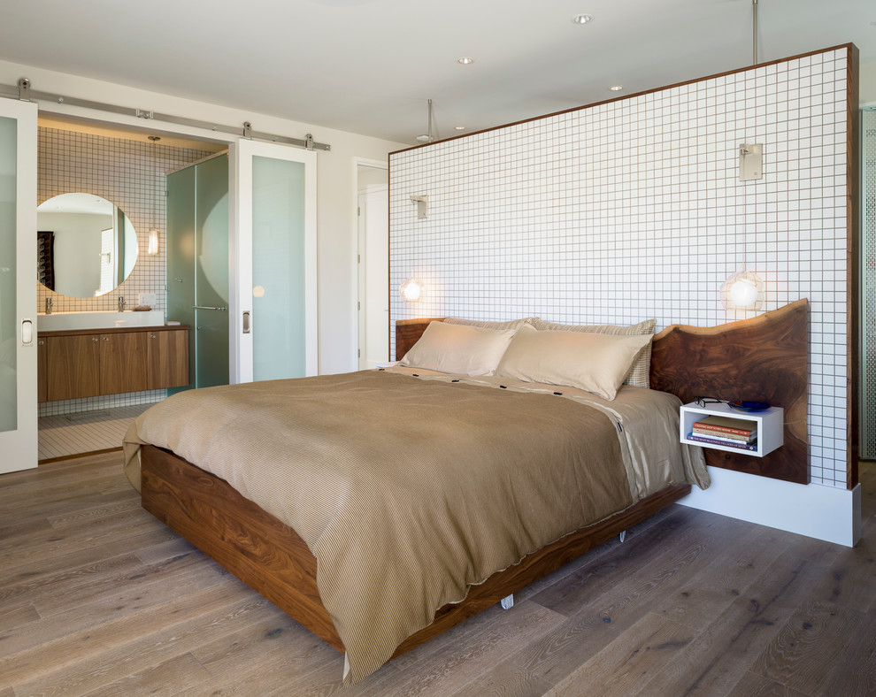 Modelo de dormitorio principal actual con paredes blancas, suelo de madera clara y suelo beige