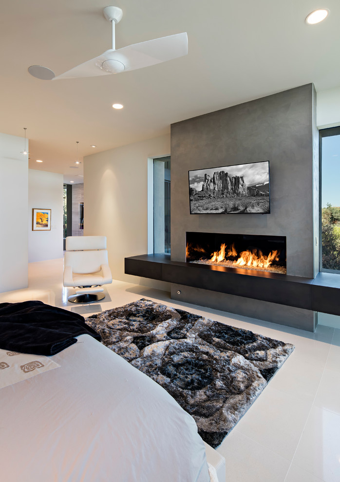 Imagen de dormitorio principal minimalista grande con paredes beige, suelo de baldosas de porcelana, chimenea lineal y marco de chimenea de hormigón