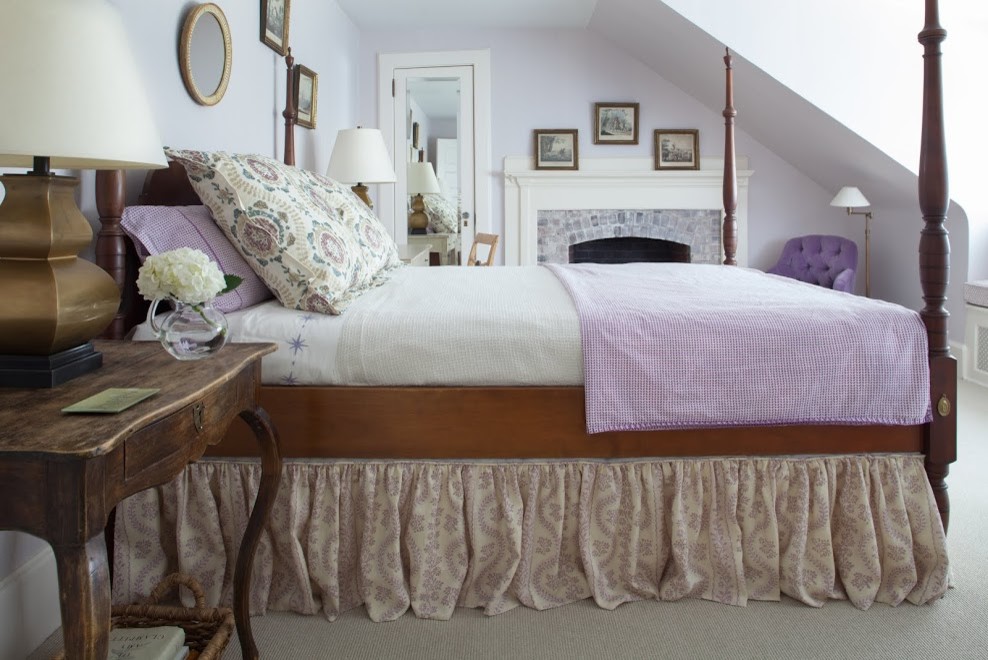 Immagine di una camera da letto chic con pareti bianche, moquette, camino classico, cornice del camino piastrellata e pavimento grigio