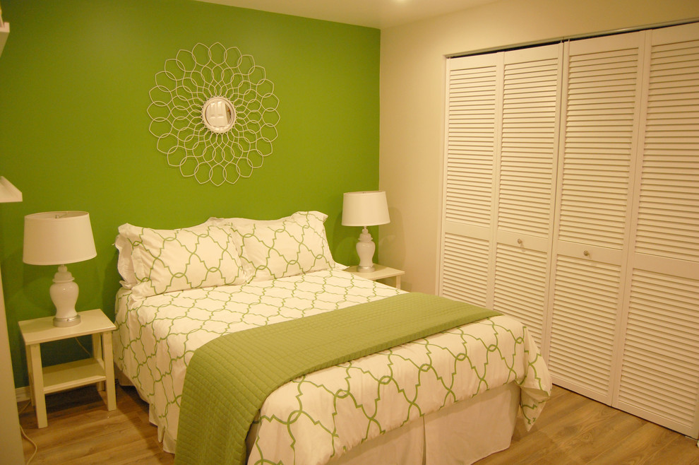 Modelo de dormitorio tradicional con paredes verdes y suelo de contrachapado