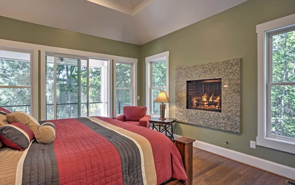 Large beach style master light wood floor bedroom photo in Orlando with green walls, a standard fireplace and a stone fireplace