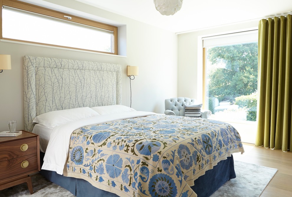 Modelo de dormitorio contemporáneo pequeño con paredes blancas, suelo de madera clara y suelo beige