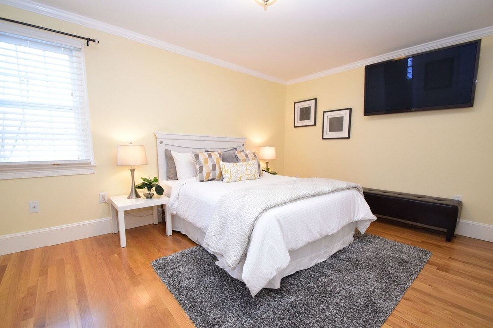 Mid-sized transitional guest medium tone wood floor and brown floor bedroom photo in Boston with yellow walls and no fireplace