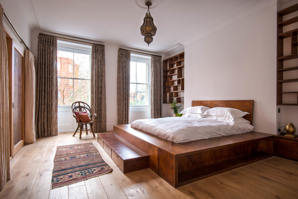 This is an example of a medium sized mediterranean bedroom in London with light hardwood flooring, beige floors, white walls and no fireplace.