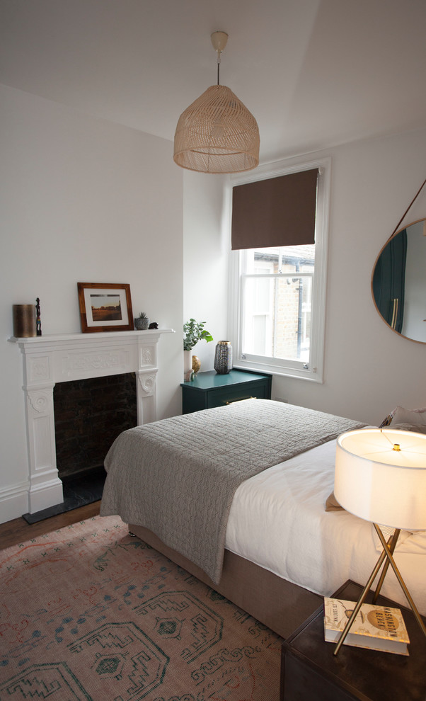 This is an example of a small contemporary master bedroom in London with grey walls, dark hardwood flooring, a standard fireplace, a plastered fireplace surround and brown floors.