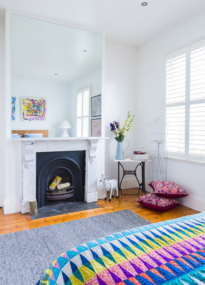 Photo of a bohemian guest bedroom in Melbourne with a standard fireplace, white walls, medium hardwood flooring and a stone fireplace surround.