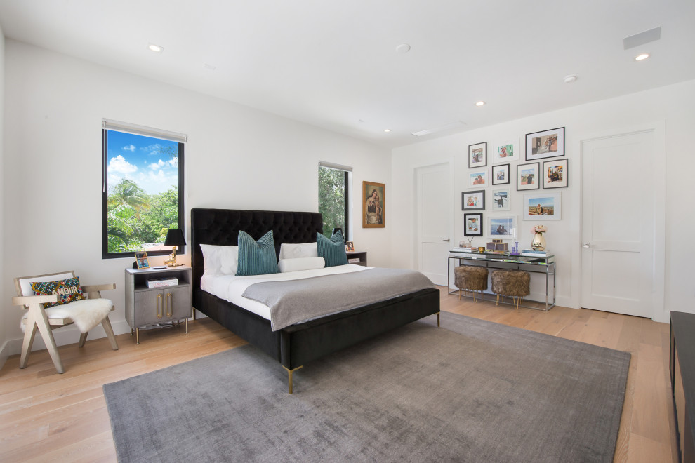 Photo of a contemporary bedroom in Miami with white walls, medium hardwood flooring and brown floors.