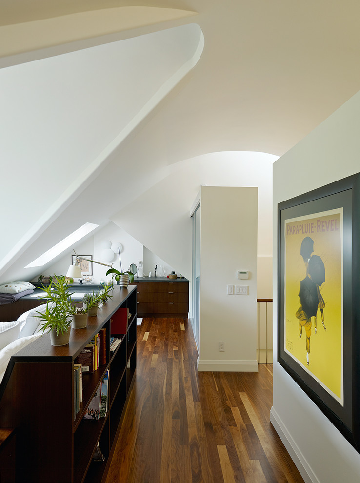 Exemple d'une grande chambre mansardée ou avec mezzanine tendance avec un mur blanc et un sol en bois brun.