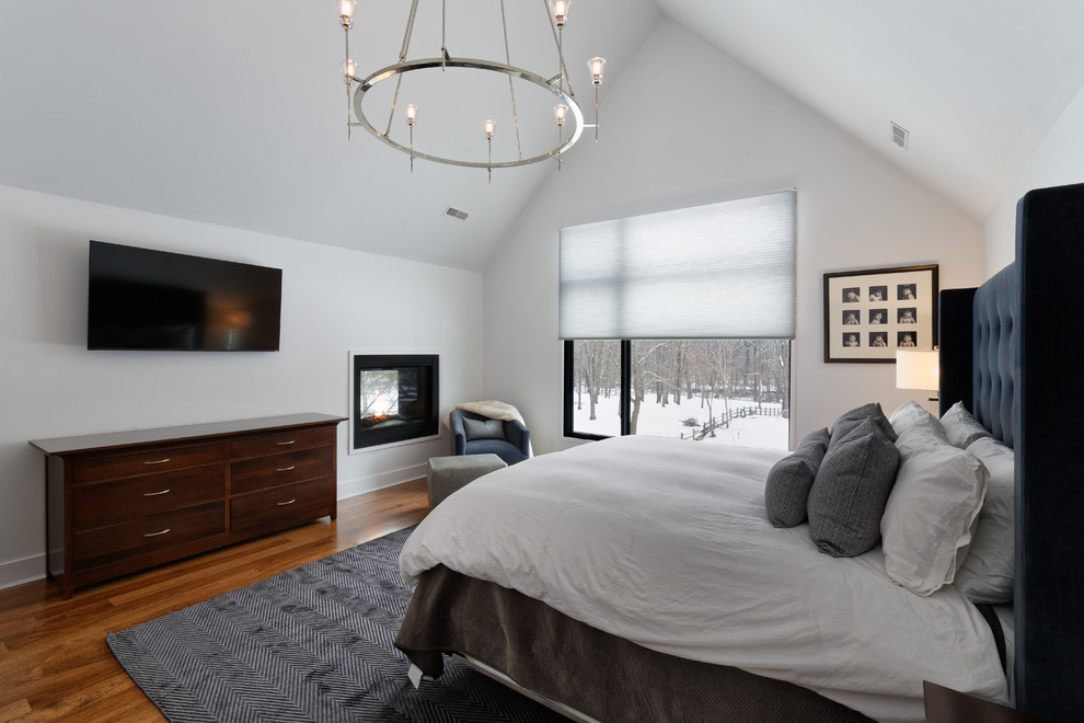Modernes Hauptschlafzimmer mit braunem Holzboden, braunem Boden, Tunnelkamin und weißer Wandfarbe in Cincinnati
