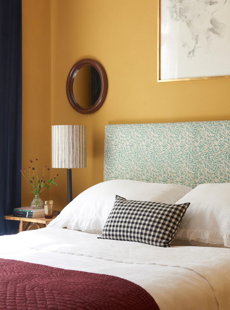 Example of an eclectic bedroom design in London with yellow walls