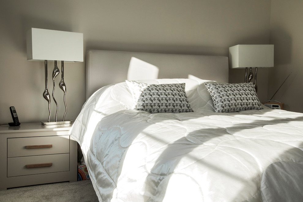 Modelo de dormitorio principal actual de tamaño medio con moqueta, paredes beige y suelo beige