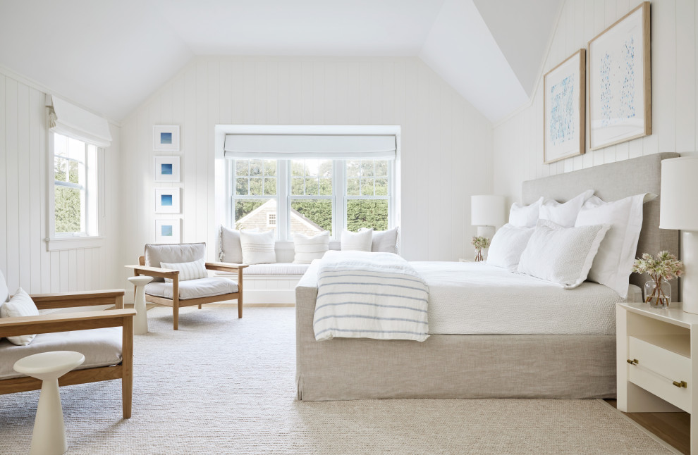 ニューヨークにある中くらいなビーチスタイルのおしゃれな主寝室 (白い壁、標準型暖炉、石材の暖炉まわり、茶色い床、無垢フローリング、三角天井)