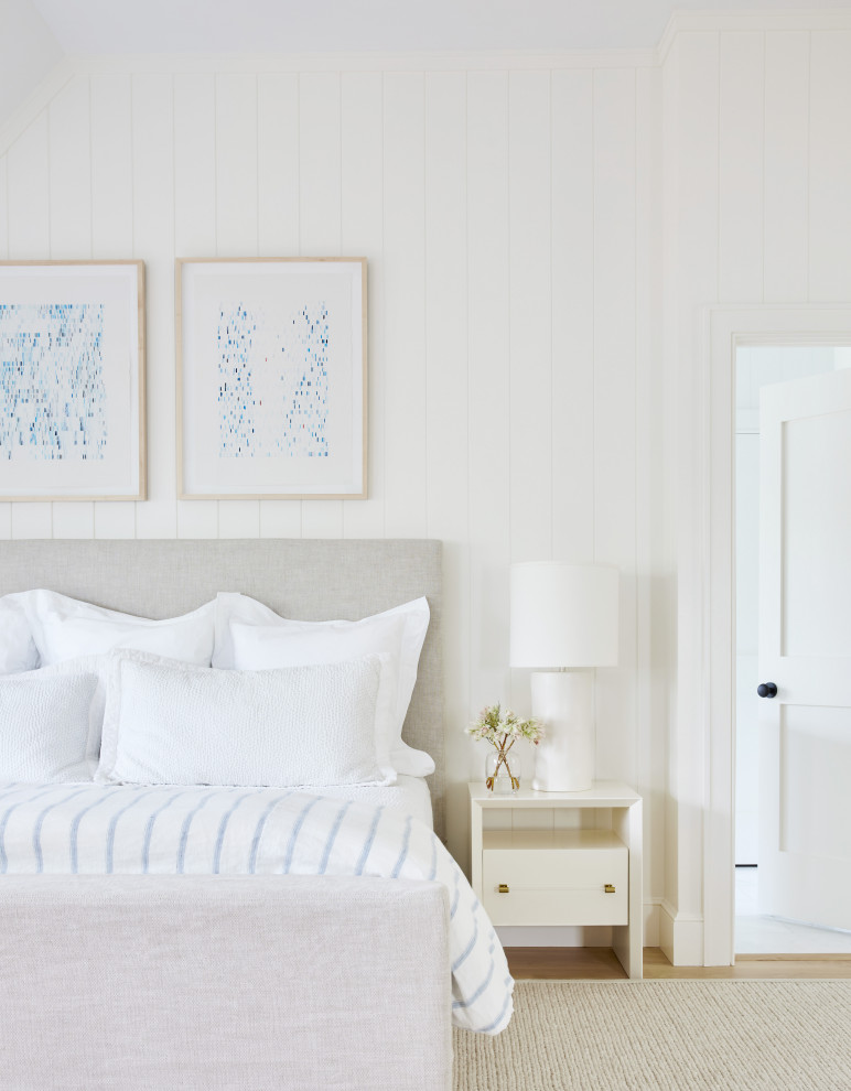 ニューヨークにある中くらいなビーチスタイルのおしゃれな主寝室 (白い壁、淡色無垢フローリング、標準型暖炉、石材の暖炉まわり、茶色い床) のインテリア