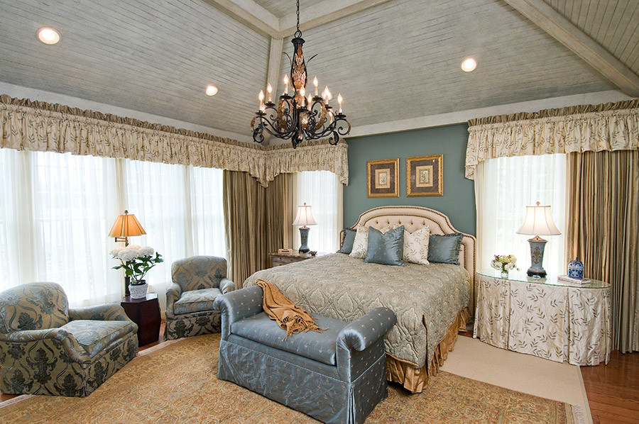 Imagen de dormitorio principal tradicional grande sin chimenea con paredes azules, suelo de madera en tonos medios y suelo marrón