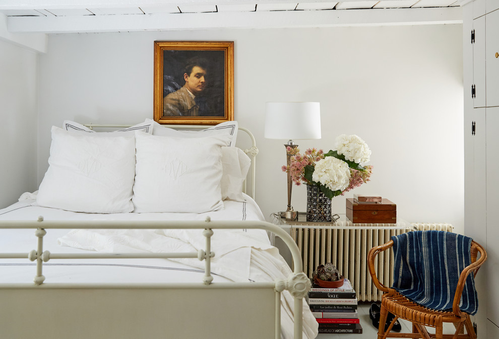 Landhaus Schlafzimmer mit weißer Wandfarbe, gebeiztem Holzboden und weißem Boden in New York