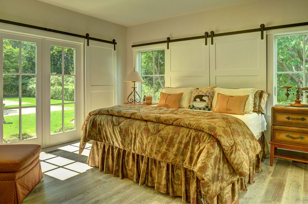 Ejemplo de dormitorio principal de estilo de casa de campo grande con paredes beige y suelo de madera clara