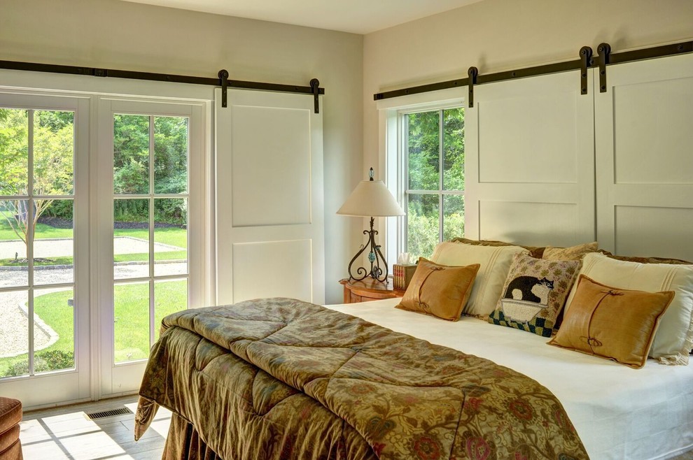 Large rural master bedroom in Burlington with beige walls and light hardwood flooring.