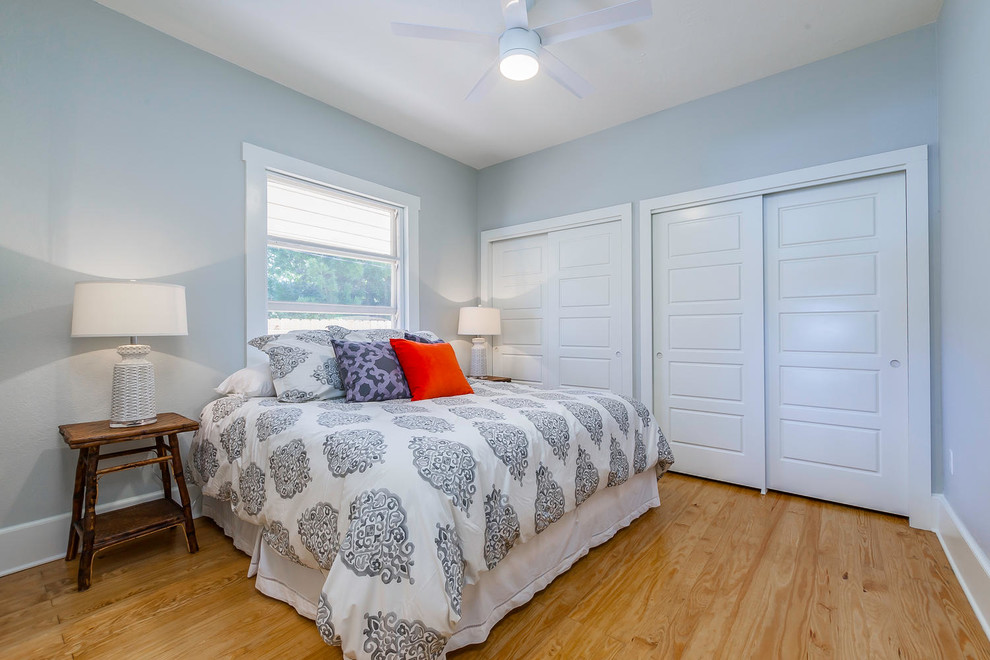 Coastal guest bedroom in Tampa with blue walls, medium hardwood flooring and beige floors.
