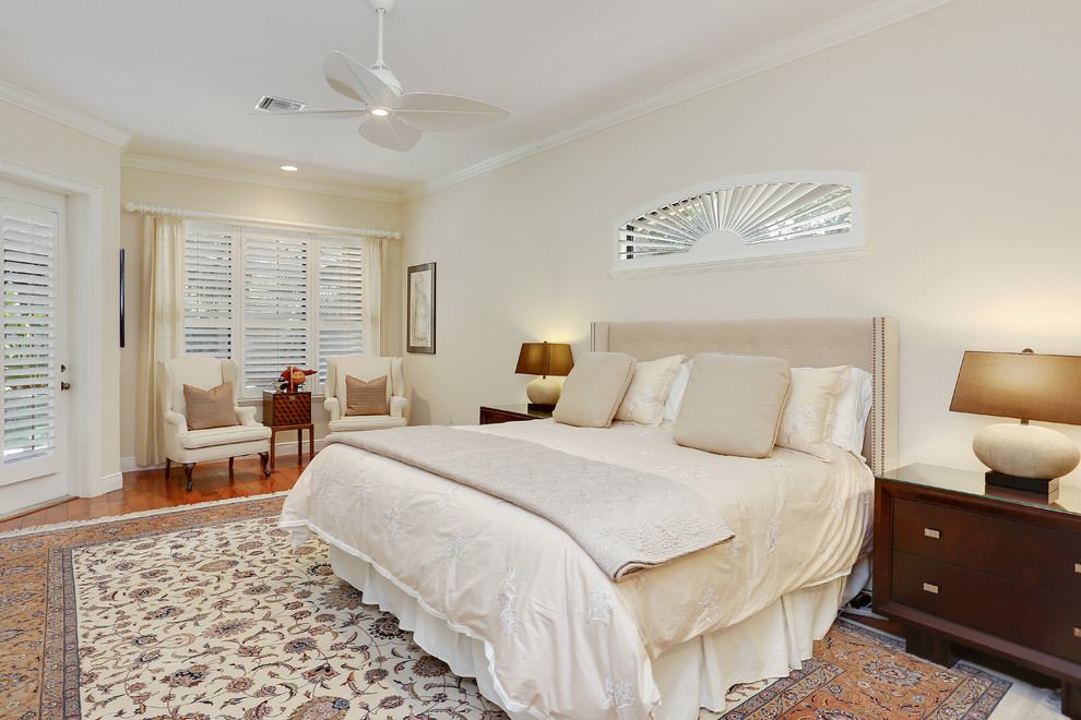 Modelo de dormitorio principal tradicional renovado grande sin chimenea con paredes beige, suelo de madera en tonos medios y suelo marrón
