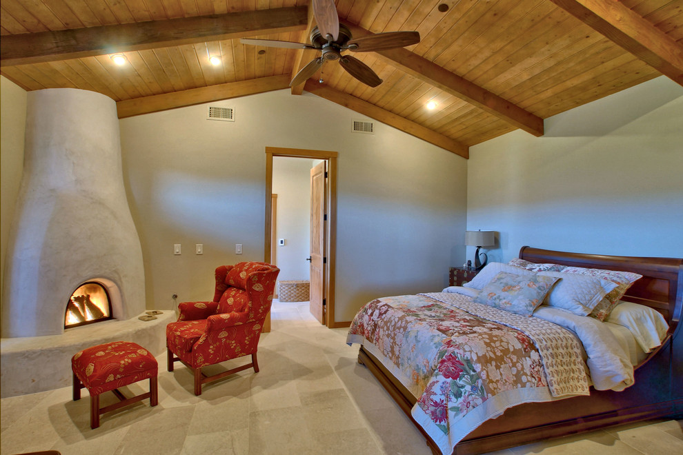 フェニックスにあるカントリー風のおしゃれな主寝室 (ベージュの壁、ライムストーンの床、コーナー設置型暖炉、漆喰の暖炉まわり、白い床) のインテリア
