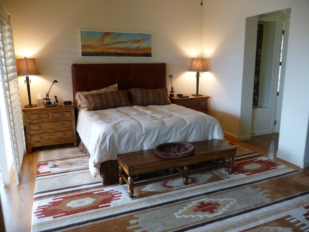 Imagen de dormitorio principal de estilo americano grande sin chimenea con paredes blancas, suelo de madera clara y suelo marrón