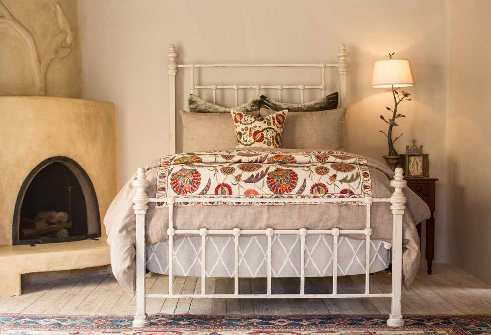 Photo of a medium sized guest bedroom in Albuquerque with beige walls, painted wood flooring, a corner fireplace and a plastered fireplace surround.