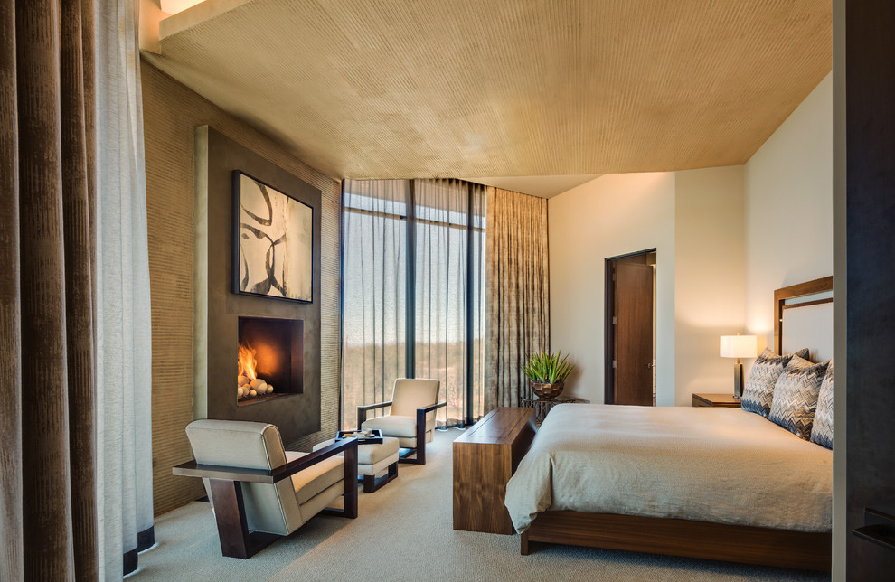 Стильный дизайн: хозяйская спальня среднего размера в современном стиле с бежевыми стенами, ковровым покрытием, стандартным камином, бежевым полом и фасадом камина из бетона - последний тренд