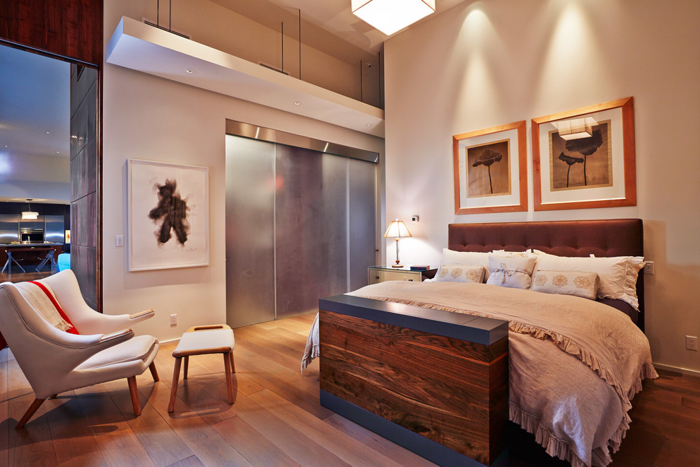 Foto de dormitorio principal contemporáneo sin chimenea con suelo de madera clara y paredes beige