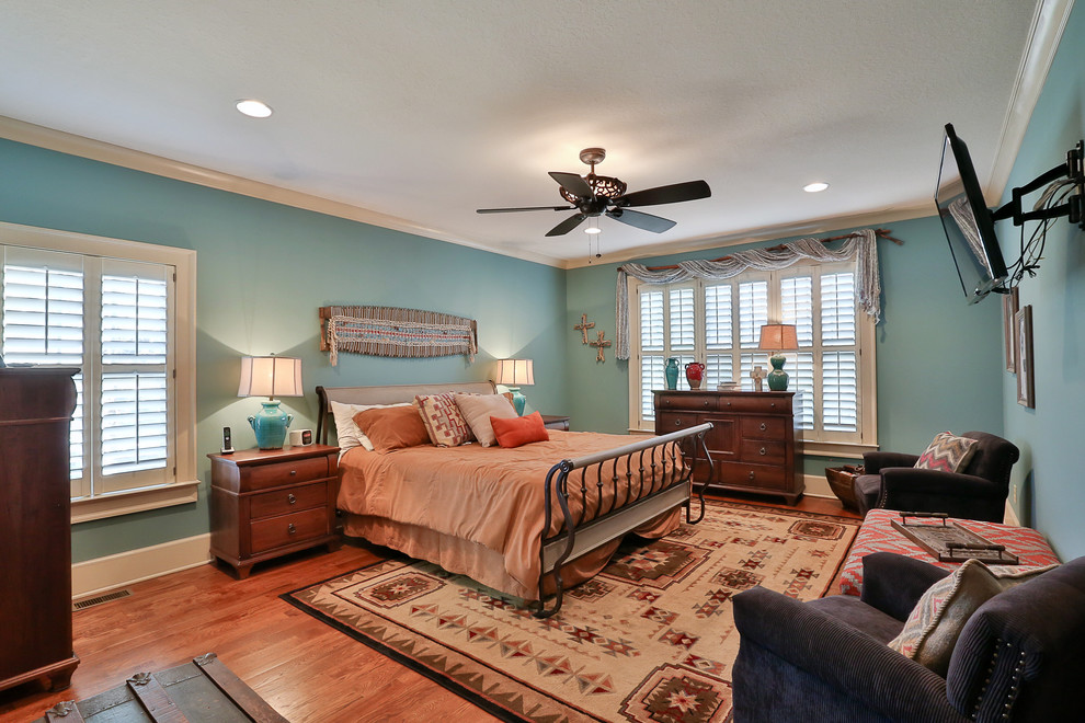 This is an example of a large master bedroom in Atlanta with blue walls, medium hardwood flooring and no fireplace.