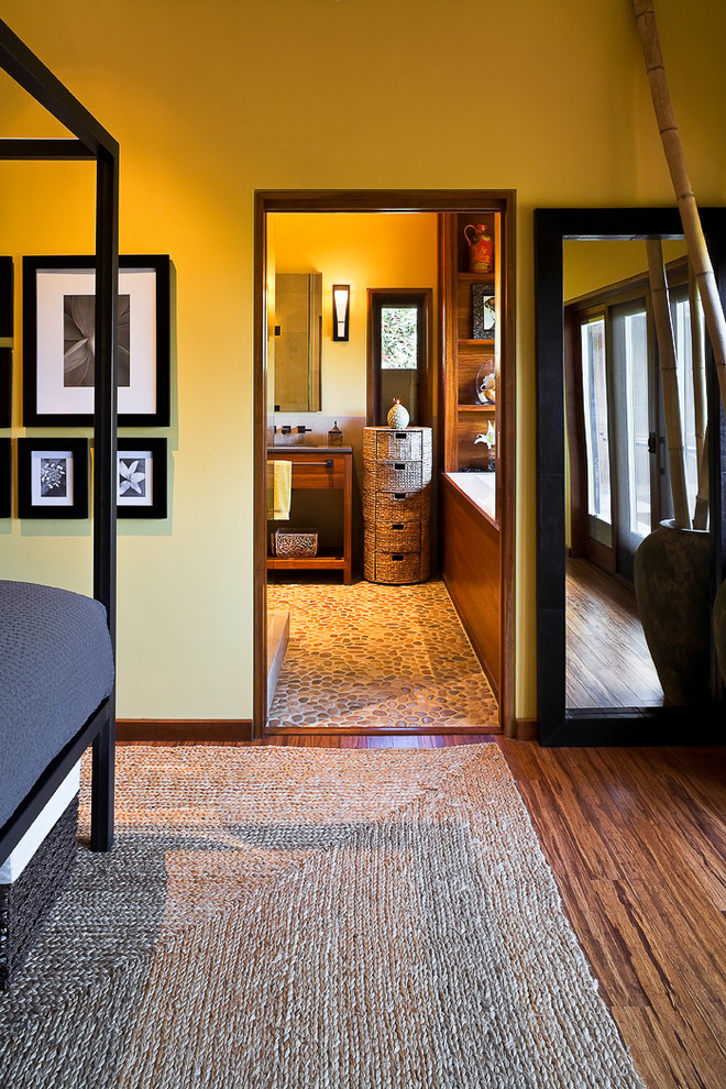 Modelo de dormitorio principal actual de tamaño medio sin chimenea con paredes amarillas, suelo de madera en tonos medios y suelo marrón