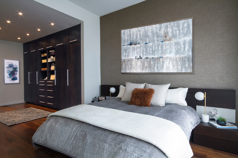 Cette image montre une chambre parentale design avec un mur gris, parquet foncé et un sol marron.
