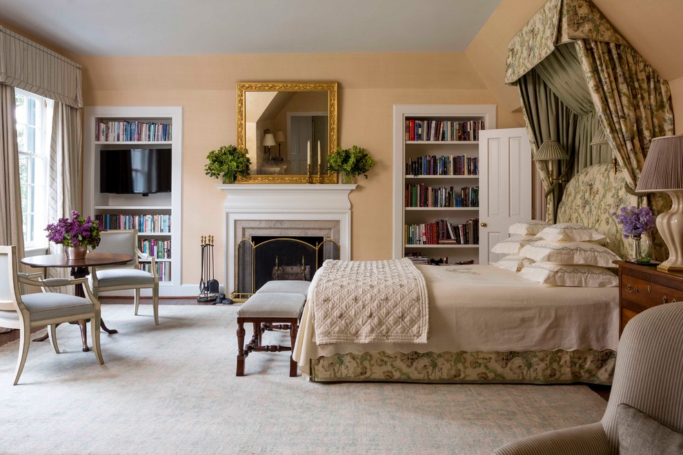 Klassisches Hauptschlafzimmer mit beiger Wandfarbe, Kamin und Kaminumrandung aus Stein in New York