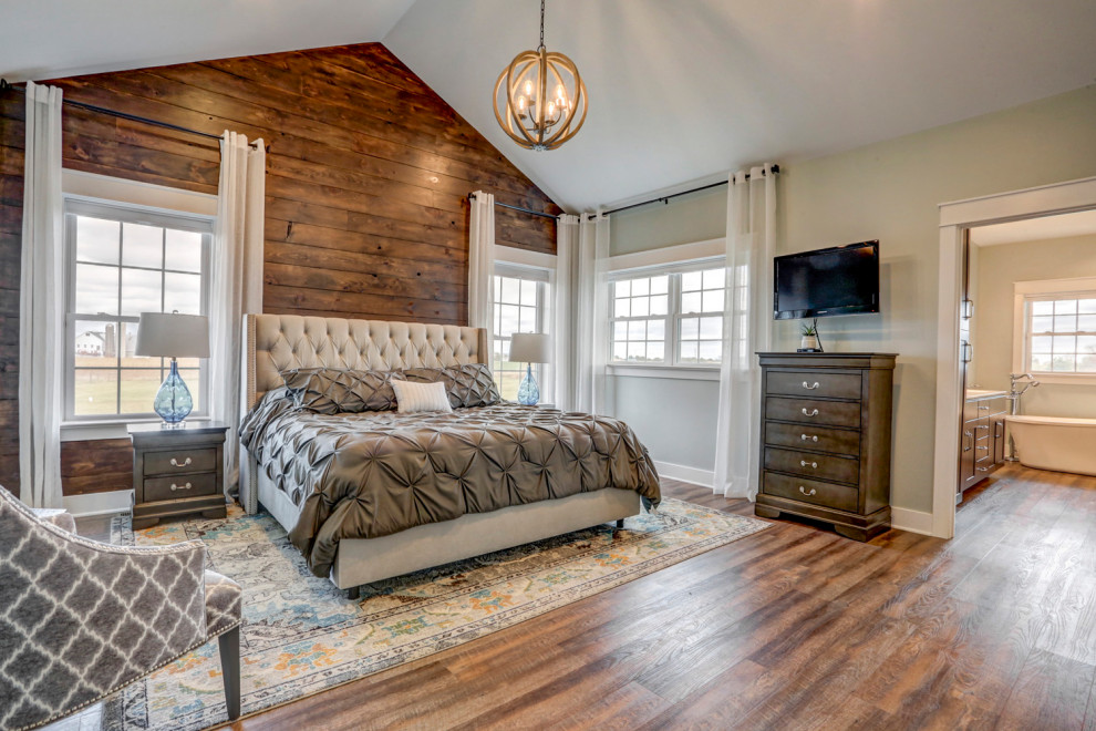 Großes Hauptschlafzimmer mit grauer Wandfarbe, Vinylboden, braunem Boden, gewölbter Decke und Holzwänden