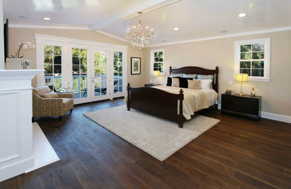 This is an example of a large contemporary master bedroom in Los Angeles with beige walls, dark hardwood flooring, a standard fireplace and brown floors.