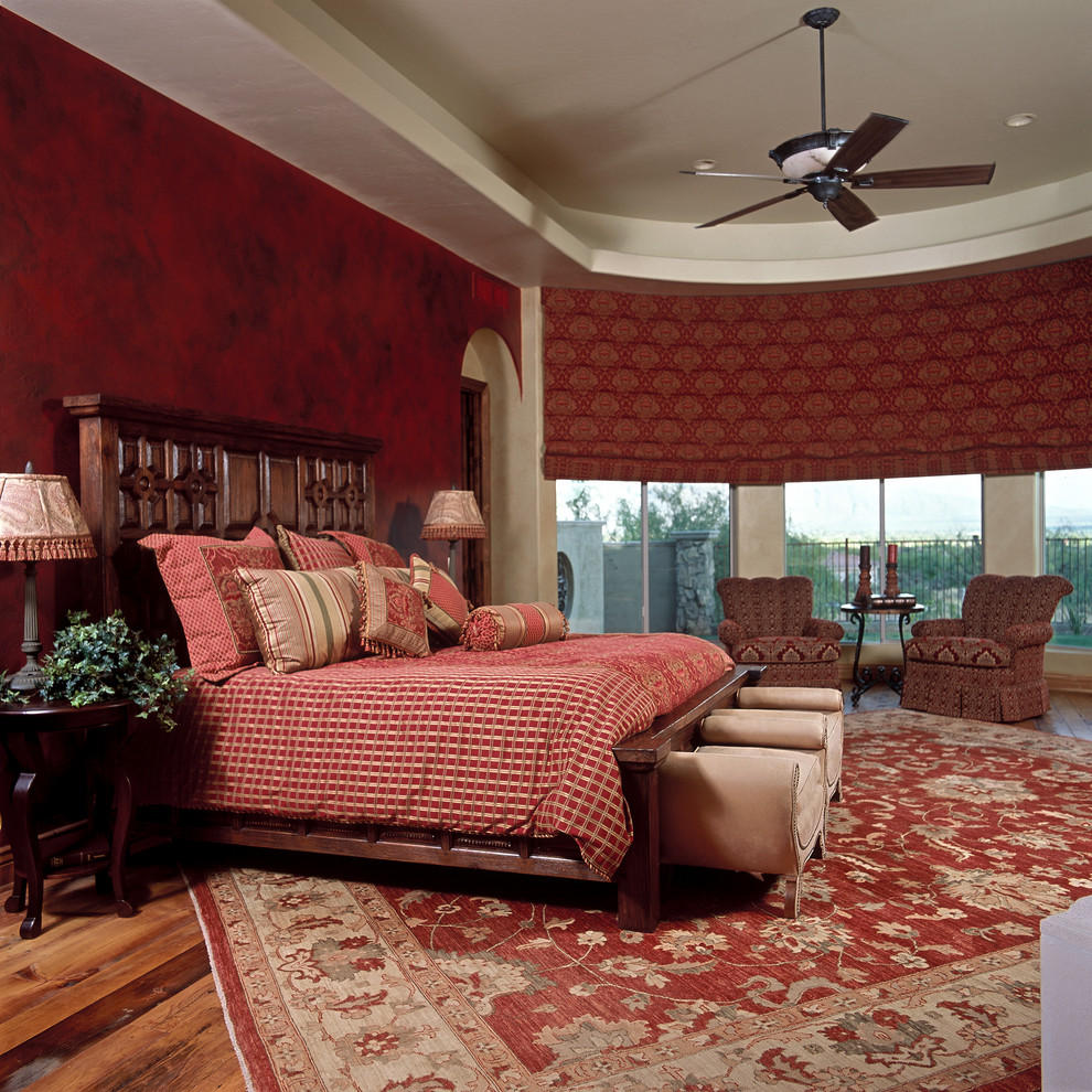 Modelo de dormitorio principal tradicional grande con paredes rojas y suelo de madera en tonos medios